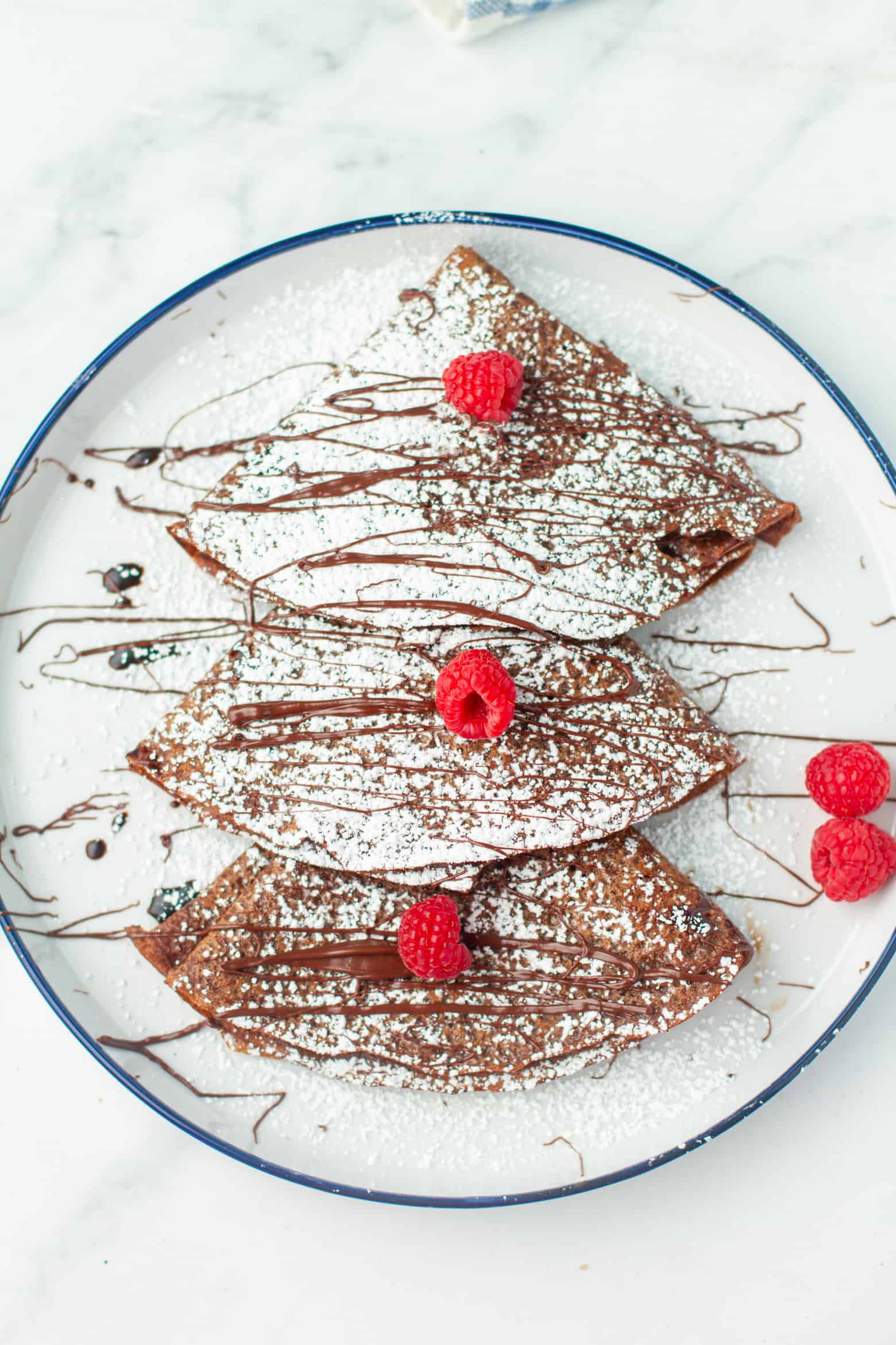 Chocolate Crepes dusted with powdered sugar and chocolate sauce.