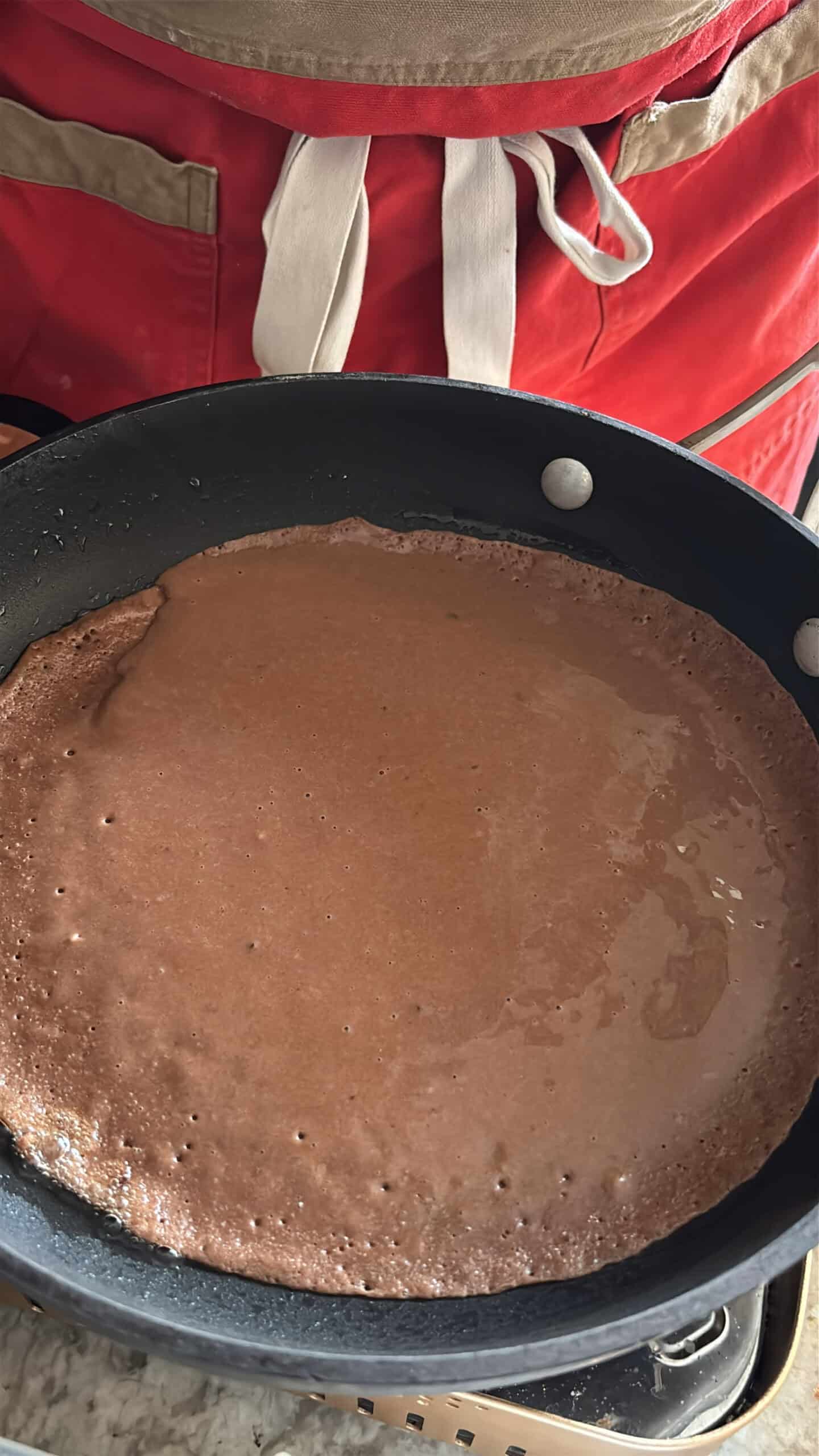 Chocolate crepes cooking in a skillet on one side.