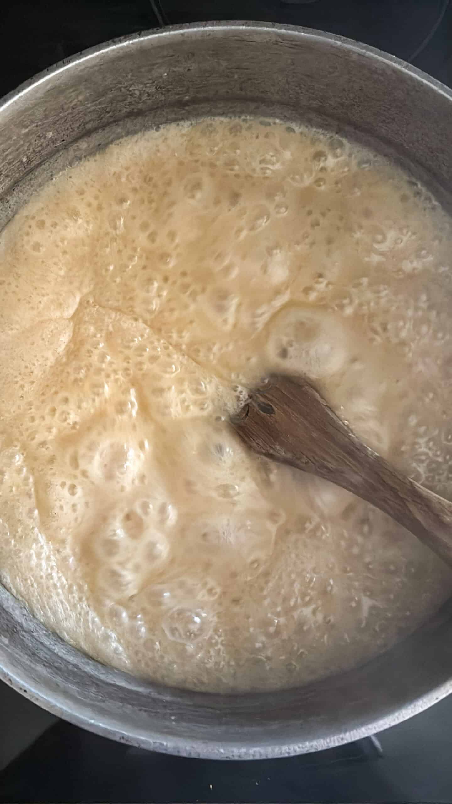 Butter, sugar, milk, and salt boiling in a pot.
