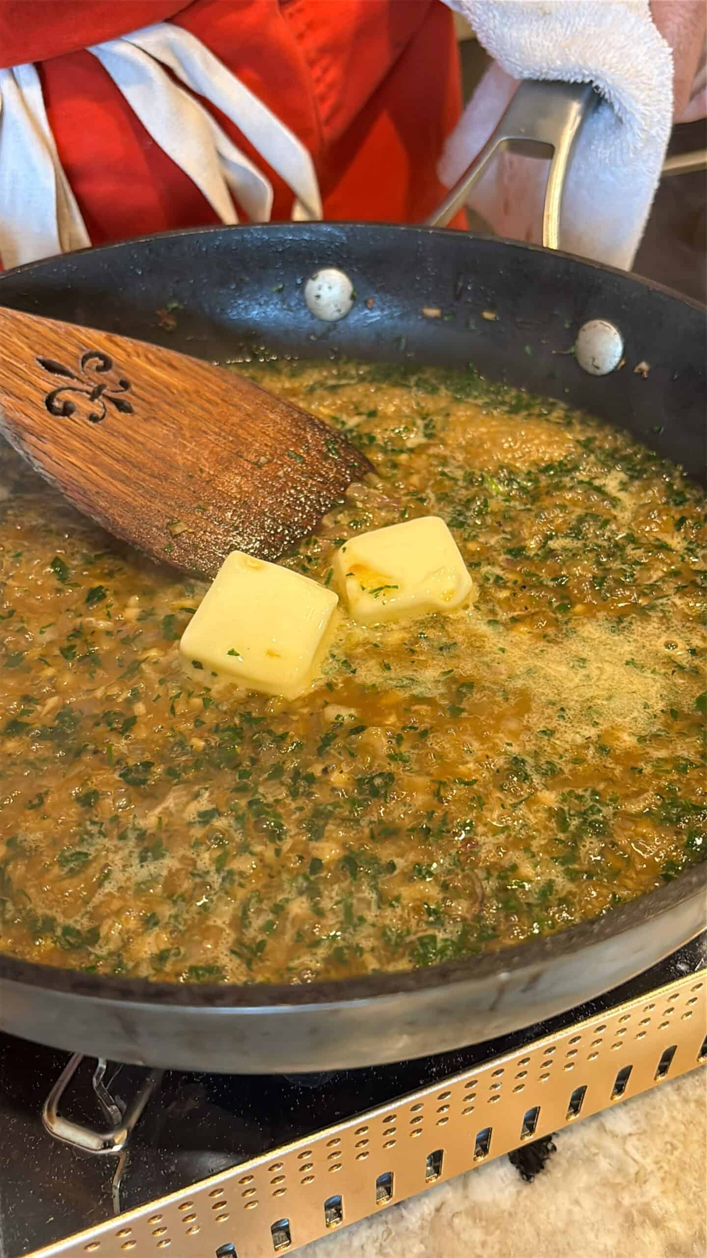 Stock and butter, Shallots, garlic and herbs cooking in a skillet.