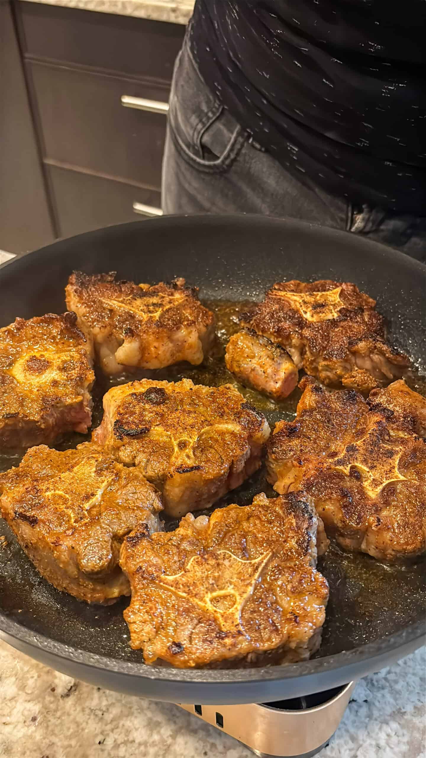 Oxtails cooking in skillet.