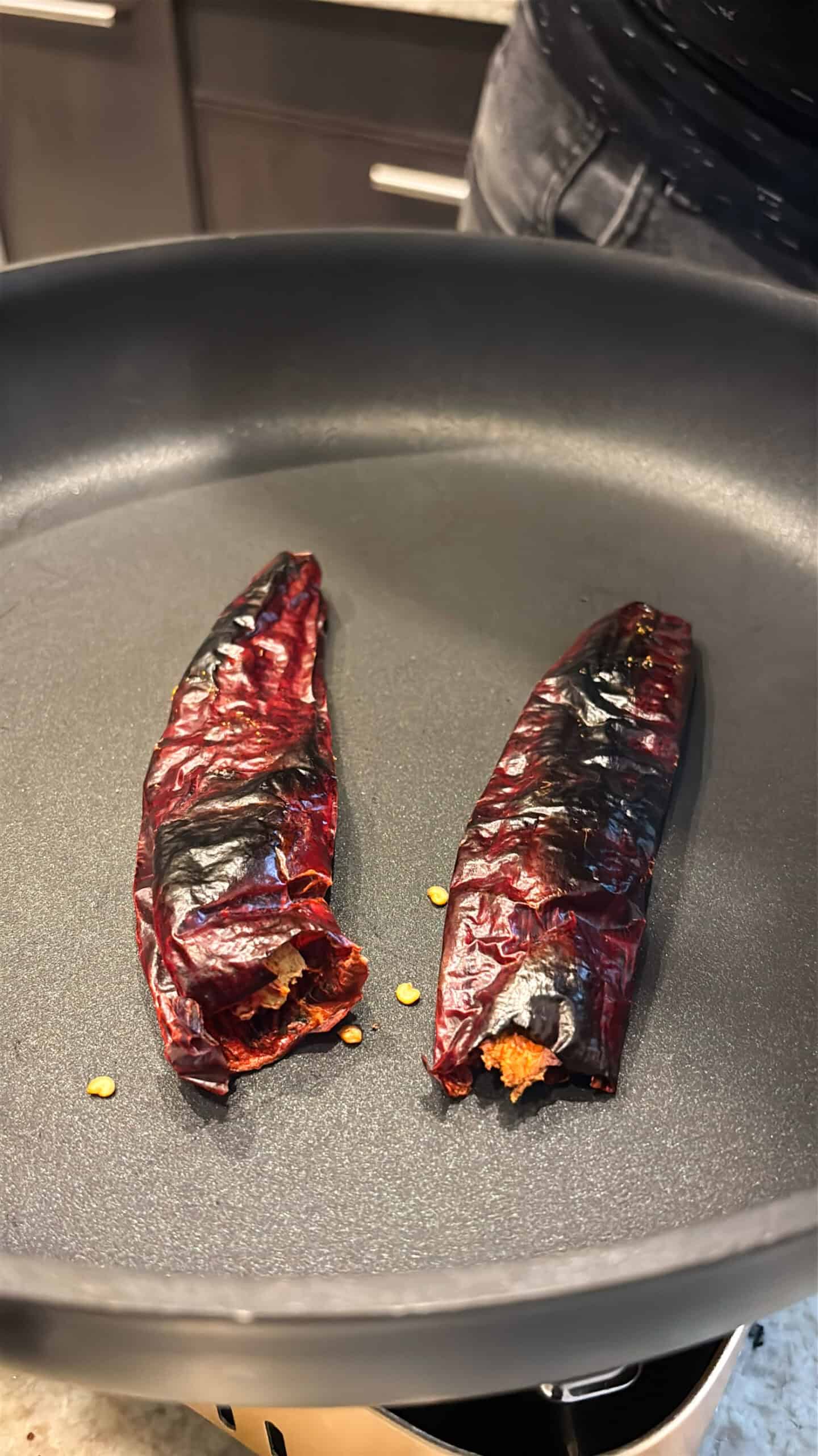 Guajillo chiles toasting in a skillet.