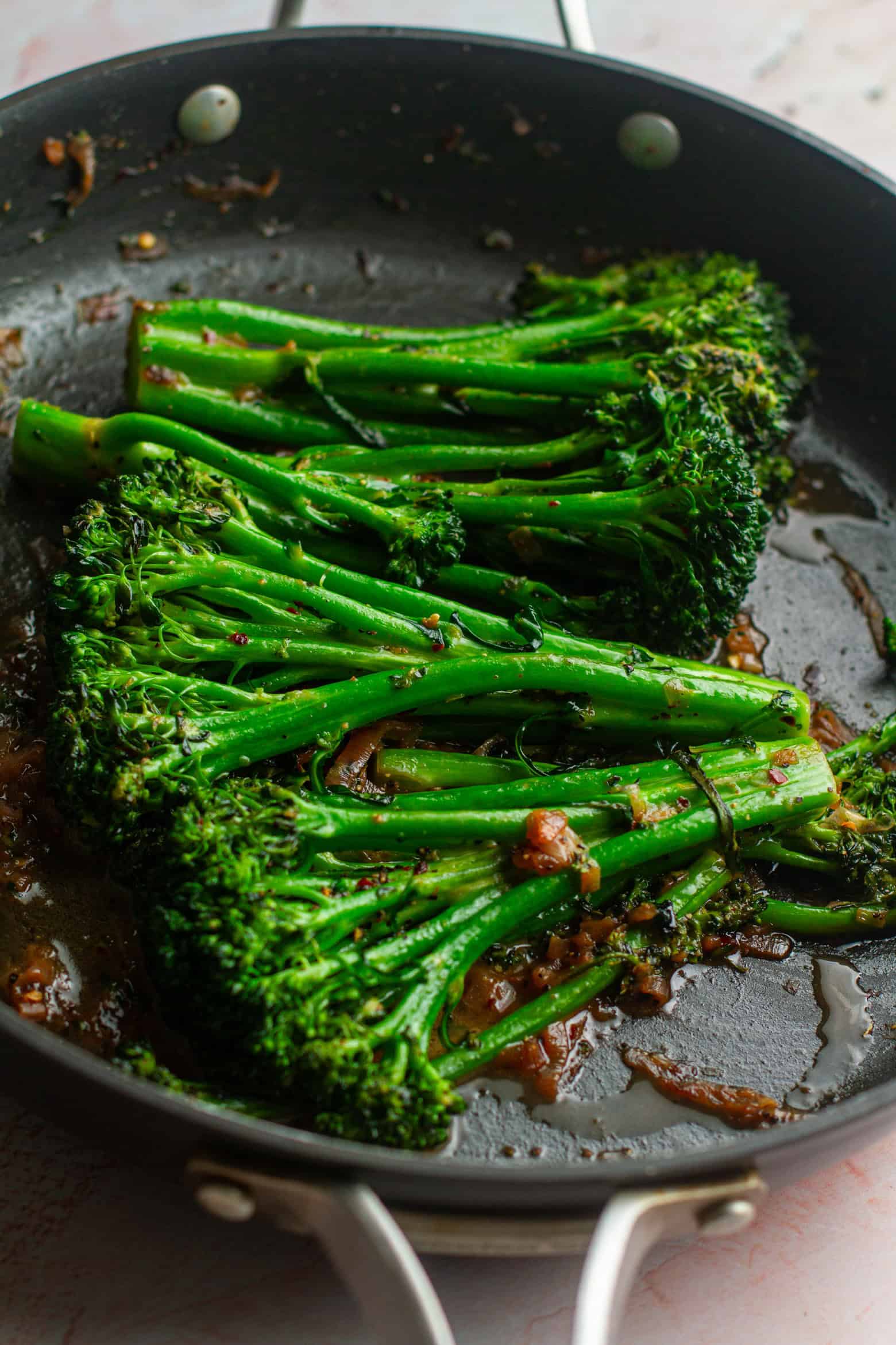 Broccolini cooking in a skillet.