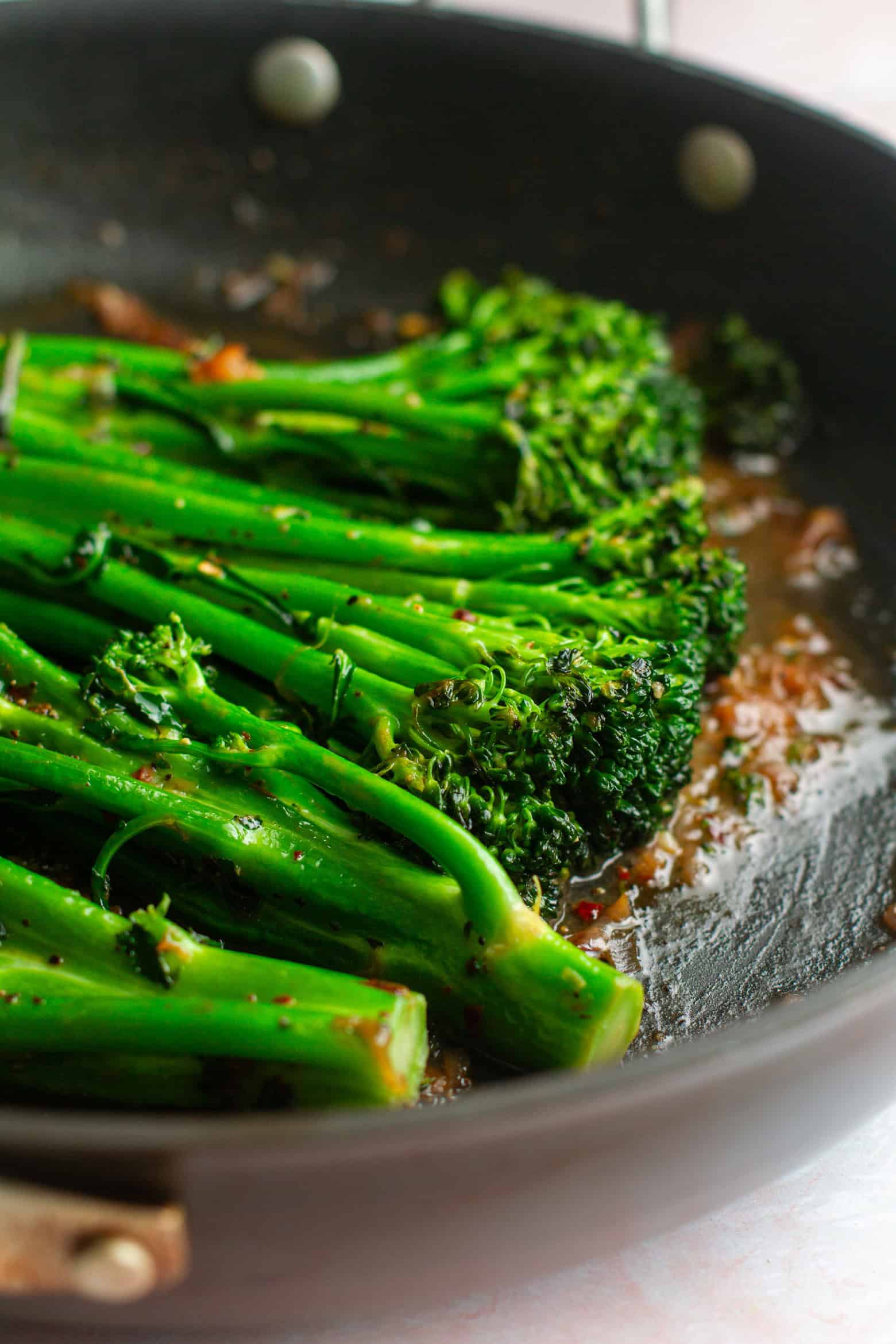 Broccolini cooking in a skillet.