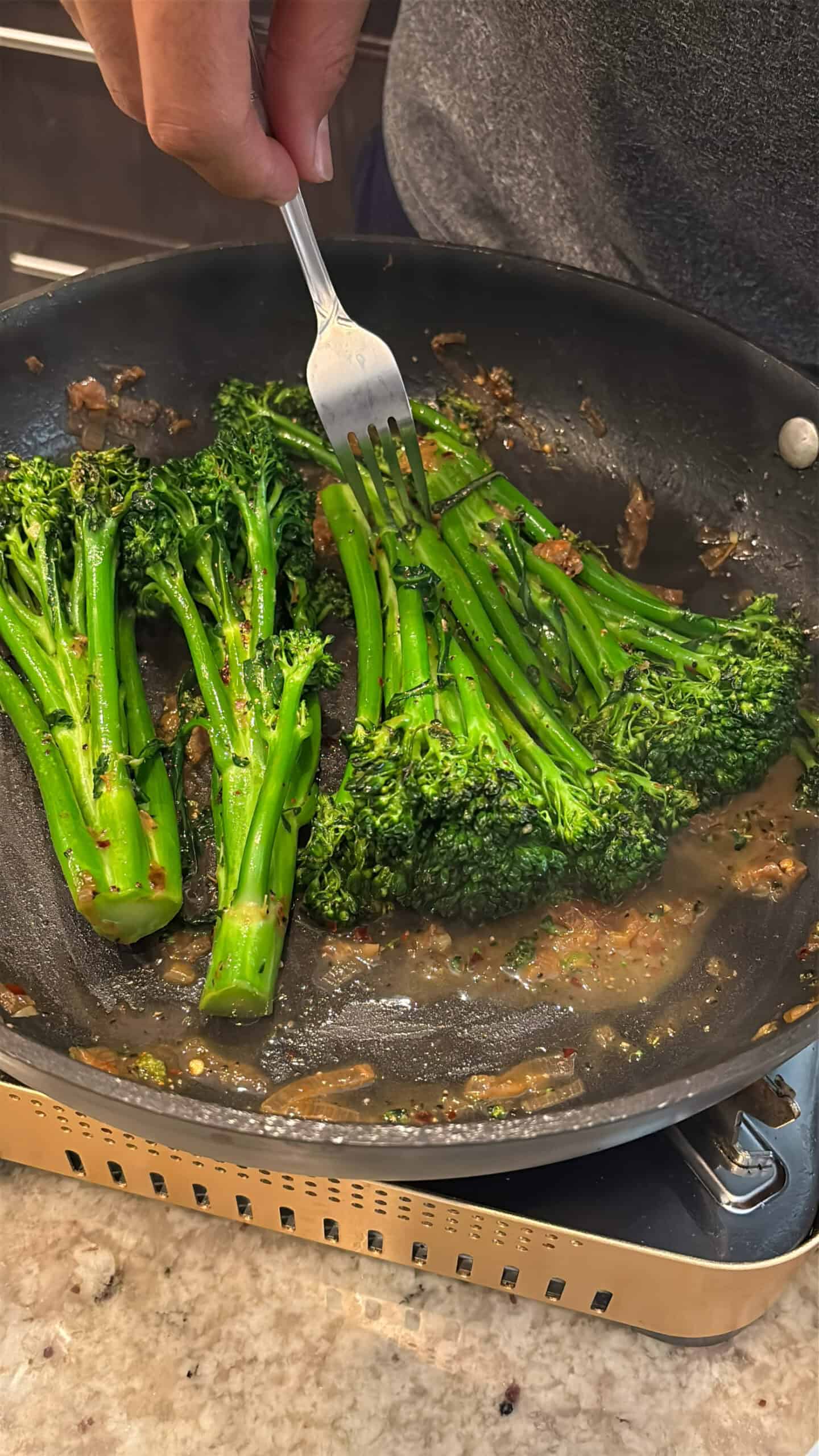 Checking to see if broccolini is fork tender.