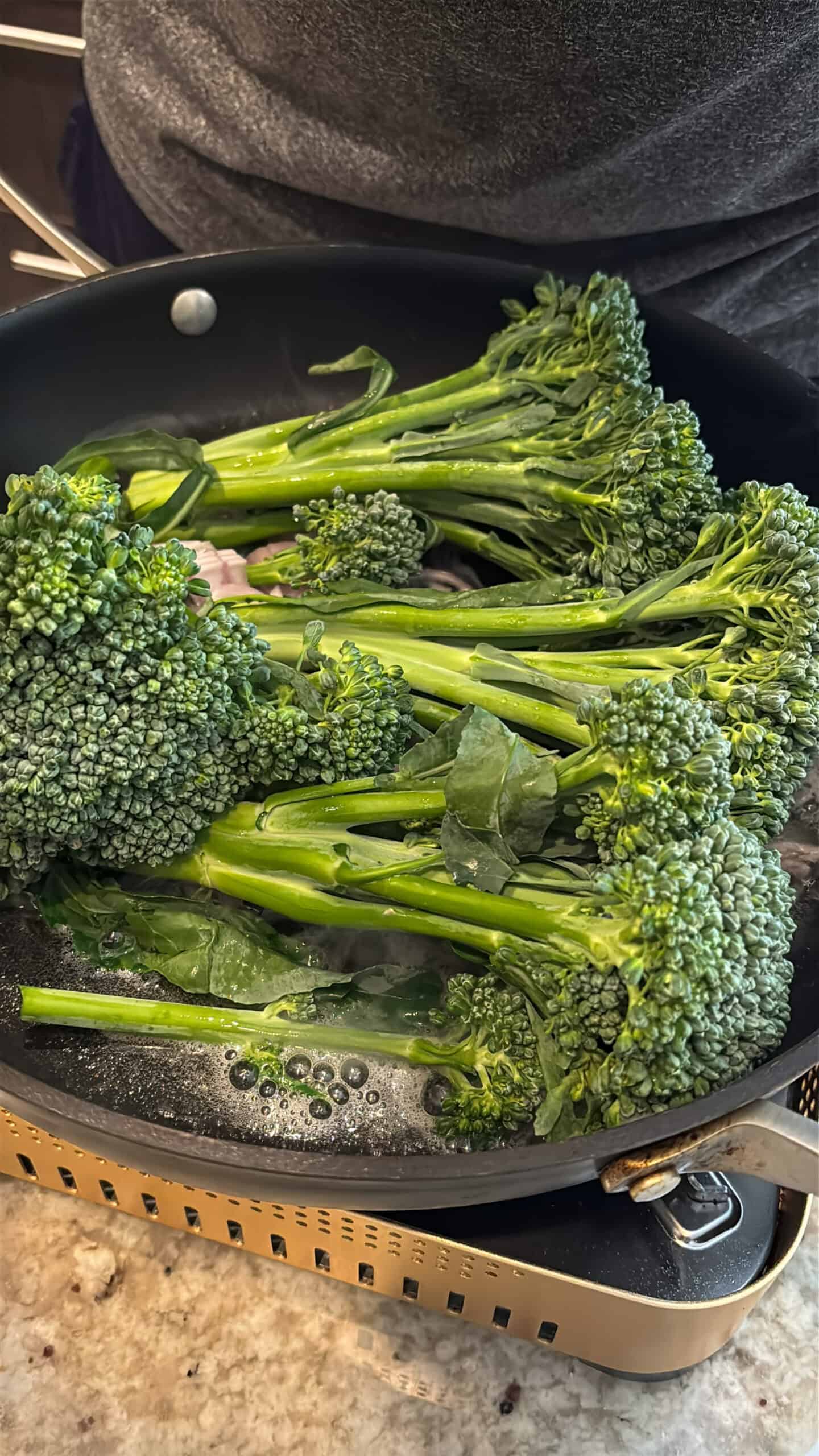 Broccolini and shallots cooking in a skillet.